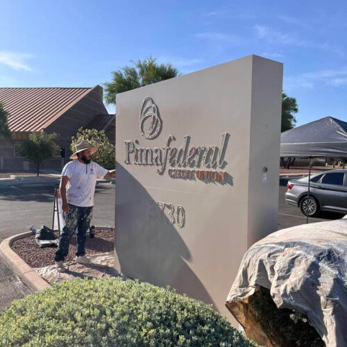 Painter from Piper Family Painting working on a commercial exterior sign for a Tucson painting project.