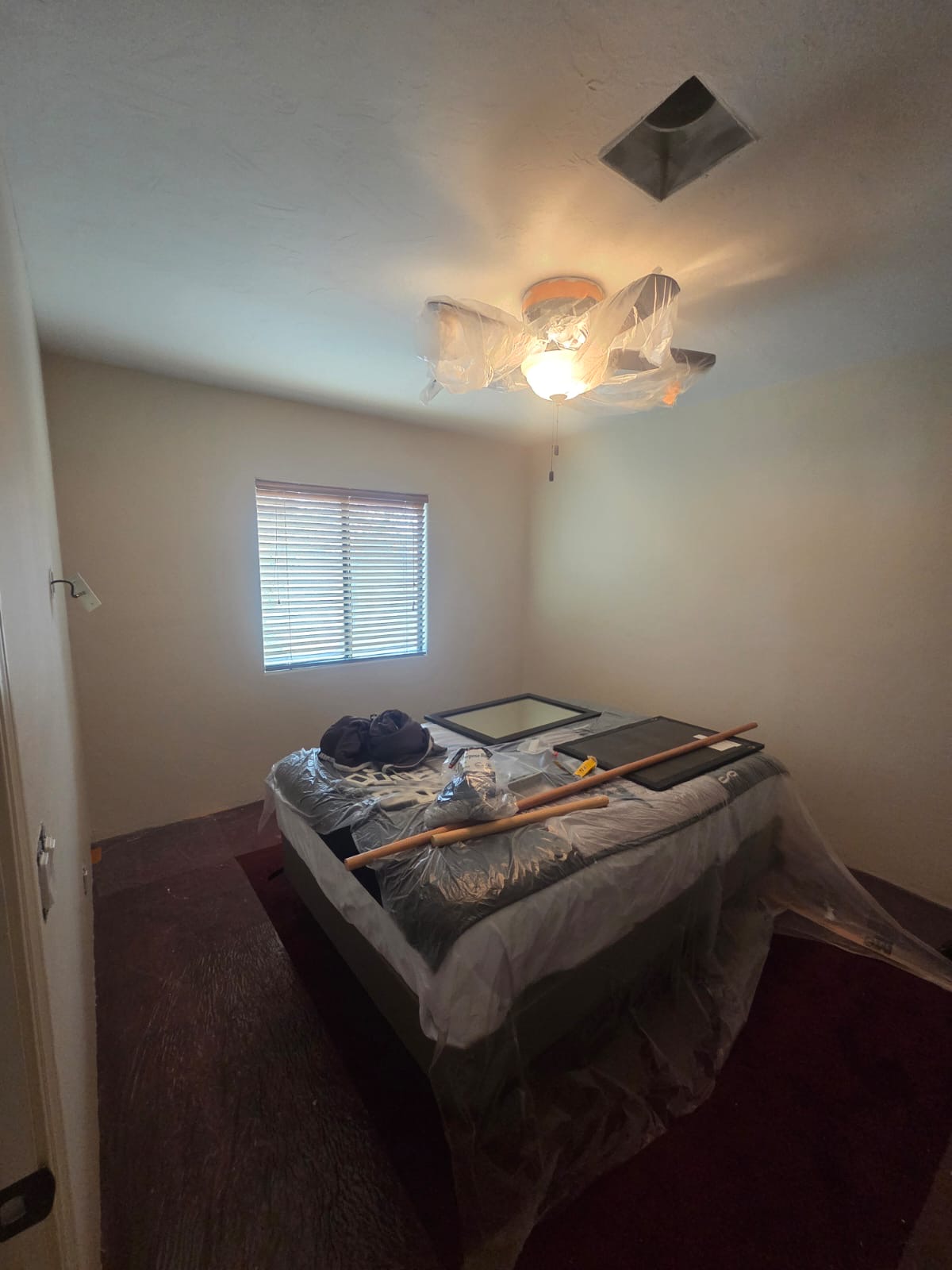 Interior painting in Tucson room with fresh neutral walls, covered furniture, painting tools, and protective plastic for a clean and professional finish.