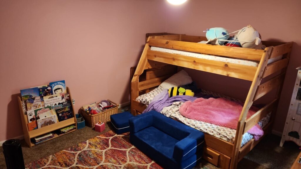 Interior painting in Tucson shown in a cozy children's bedroom with soft pink walls, wooden bunk bed, colorful rug, and playful decor elements.