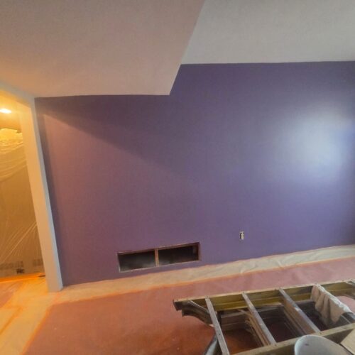 Interior painting in Tucson with a vibrant purple wall, showcasing expert craftsmanship, protective coverings, and a modern, expressive home design in progress.