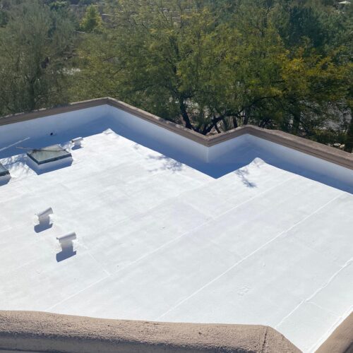 White roof coatings applied by Piper Family Painting Company enhance energy efficiency and protection on a flat rooftop surrounded by greenery and mountains.