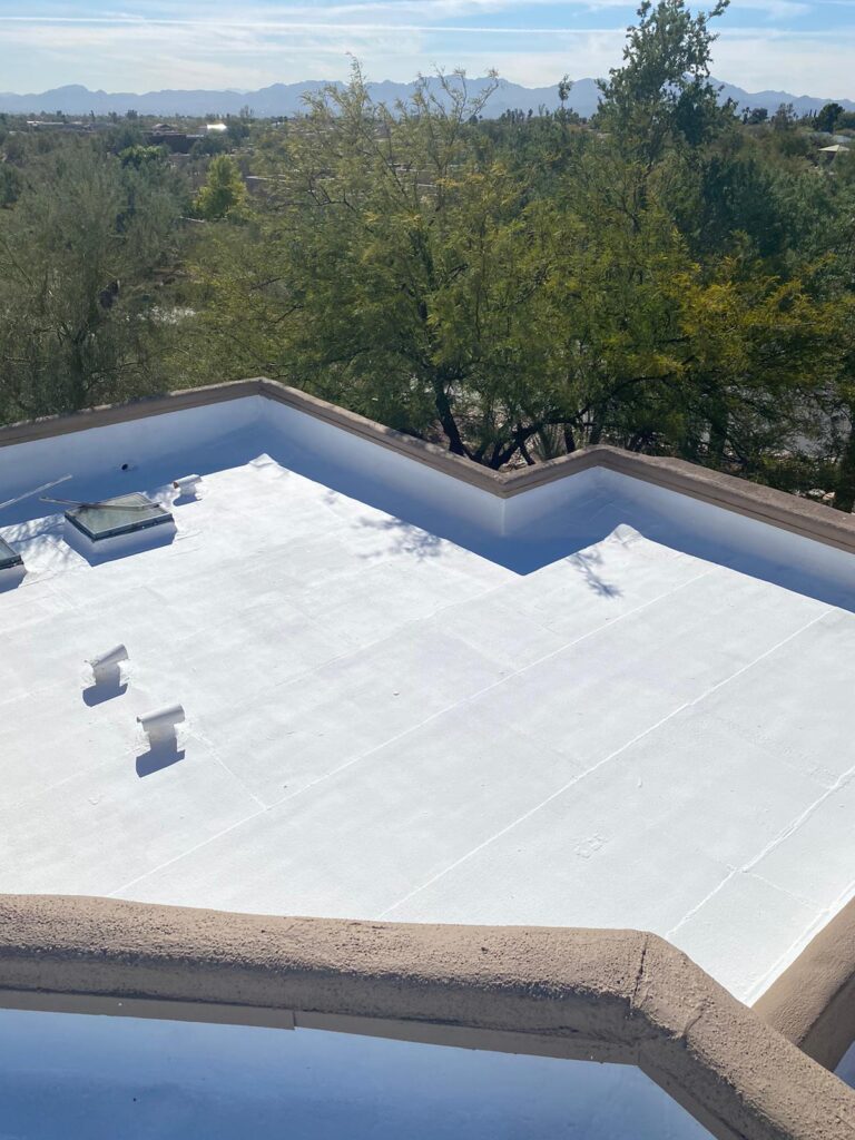 White roof coatings applied by Piper Family Painting Company enhance energy efficiency and protection on a flat rooftop surrounded by greenery and mountains.