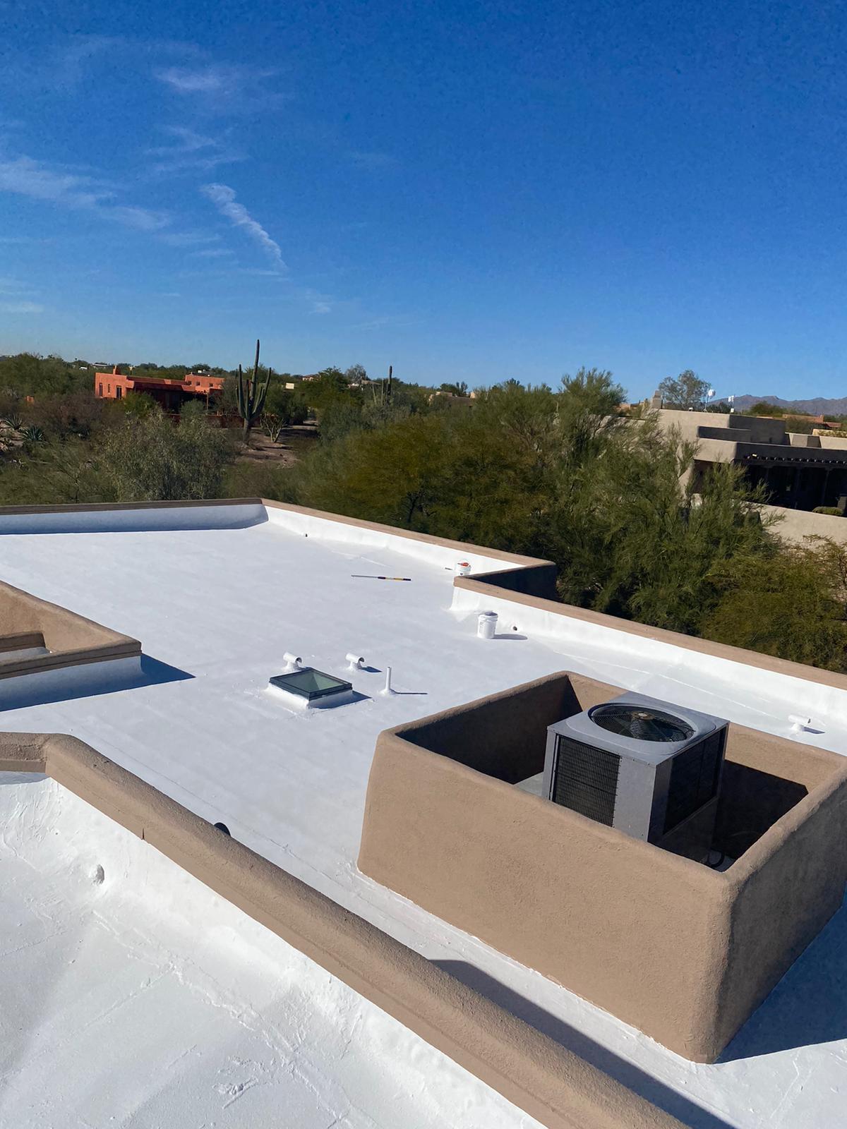 Flat roof with white roof coatings by Piper Family Painting Company, showing energy-efficient reflective surface in a sunny desert climate with HVAC and skylight.