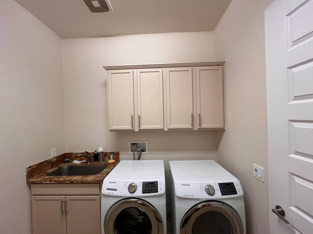 Catalina Painting Company laundry room by Piper Family Painting Company featuring soft beige walls, modern cabinetry, and a polished marble countertop.