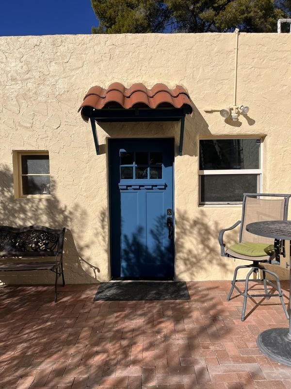 Charming exterior by Piper Family Painting Company with vibrant blue door and Mediterranean elements, showcasing Catalina Painting Company craftsmanship.