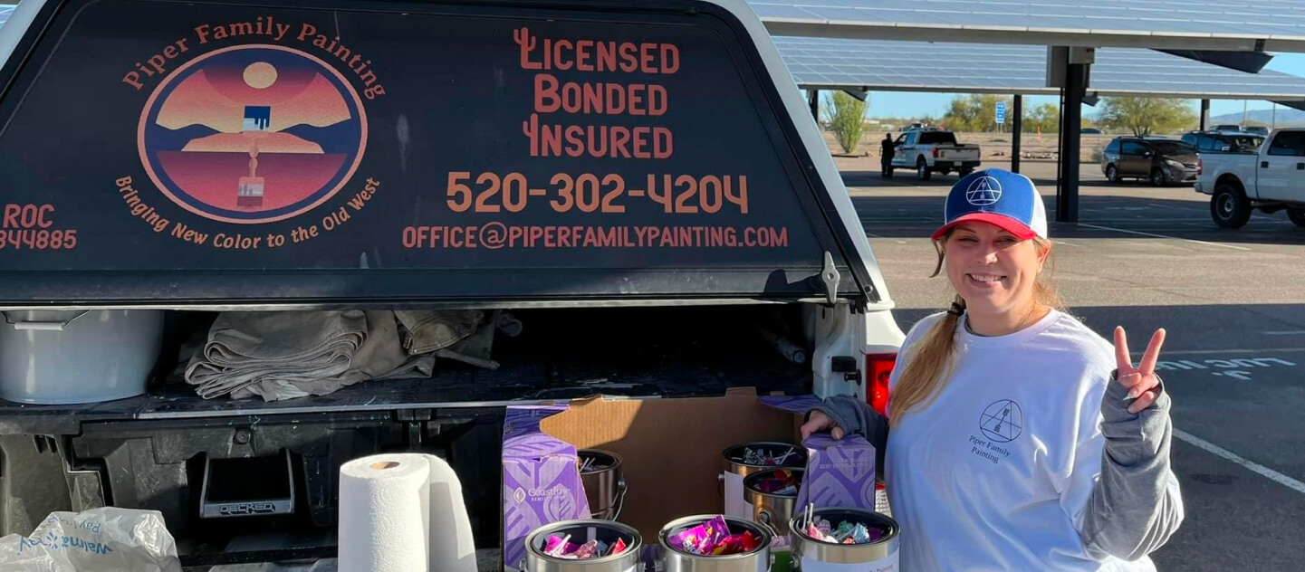 Dove Mountain Painting Company team member from Piper Family Painting Company stands beside a branded truck with supplies, ready for a professional painting project.