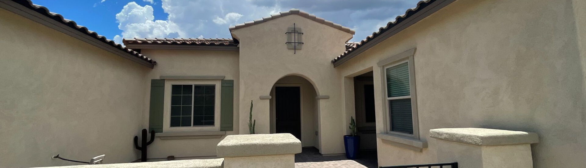 Exterior of a sunlit home painted by Piper Family Painting Company, showcasing Marana Painting Company expertise with beige stucco walls and a bold blue door.