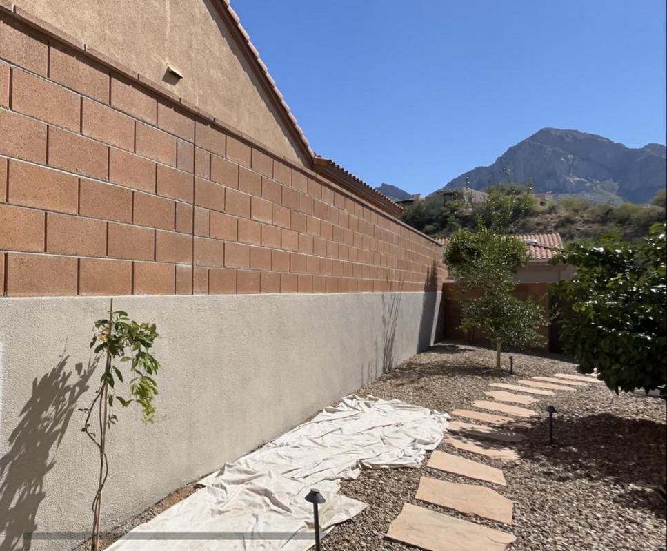 Piper Family Painting Company showcases expert exterior work in Rancho Vistoso with a freshly painted beige wall and scenic garden path under a clear blue sky.