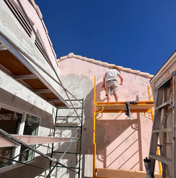 Piper Family Painting Company painter from Sahuarita Painting Company works on a home's exterior under a clear sky, showcasing expert residential painting services.