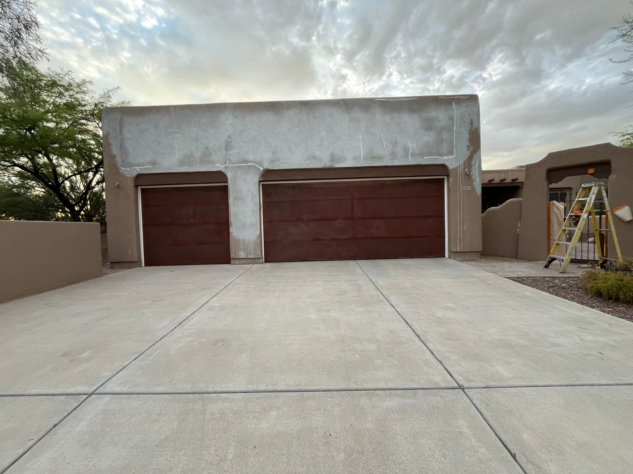 Piper Family Painting Company stucco repair on a residential home garage showcasing smooth, uniform stucco finish under bright sunlight and desert landscaping.